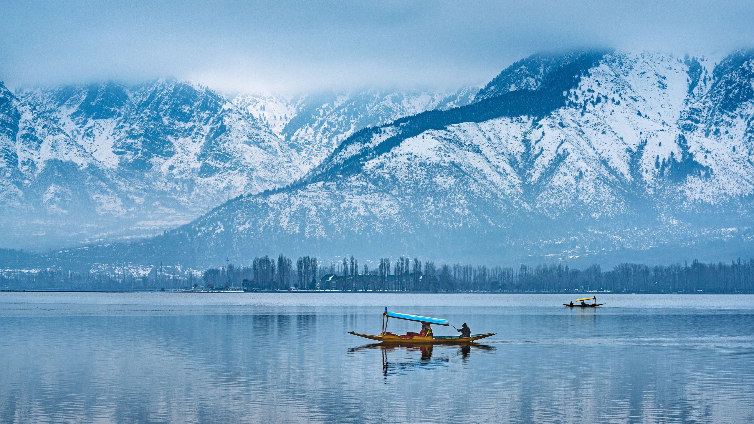 Traditional shikara boat on Dal Lake with Himalayas in the background in Srinagar, Kashmir